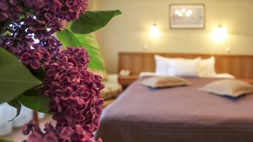 A hotel room with a bed, pillows, a nightstand, and a wall-mounted light fixture.
