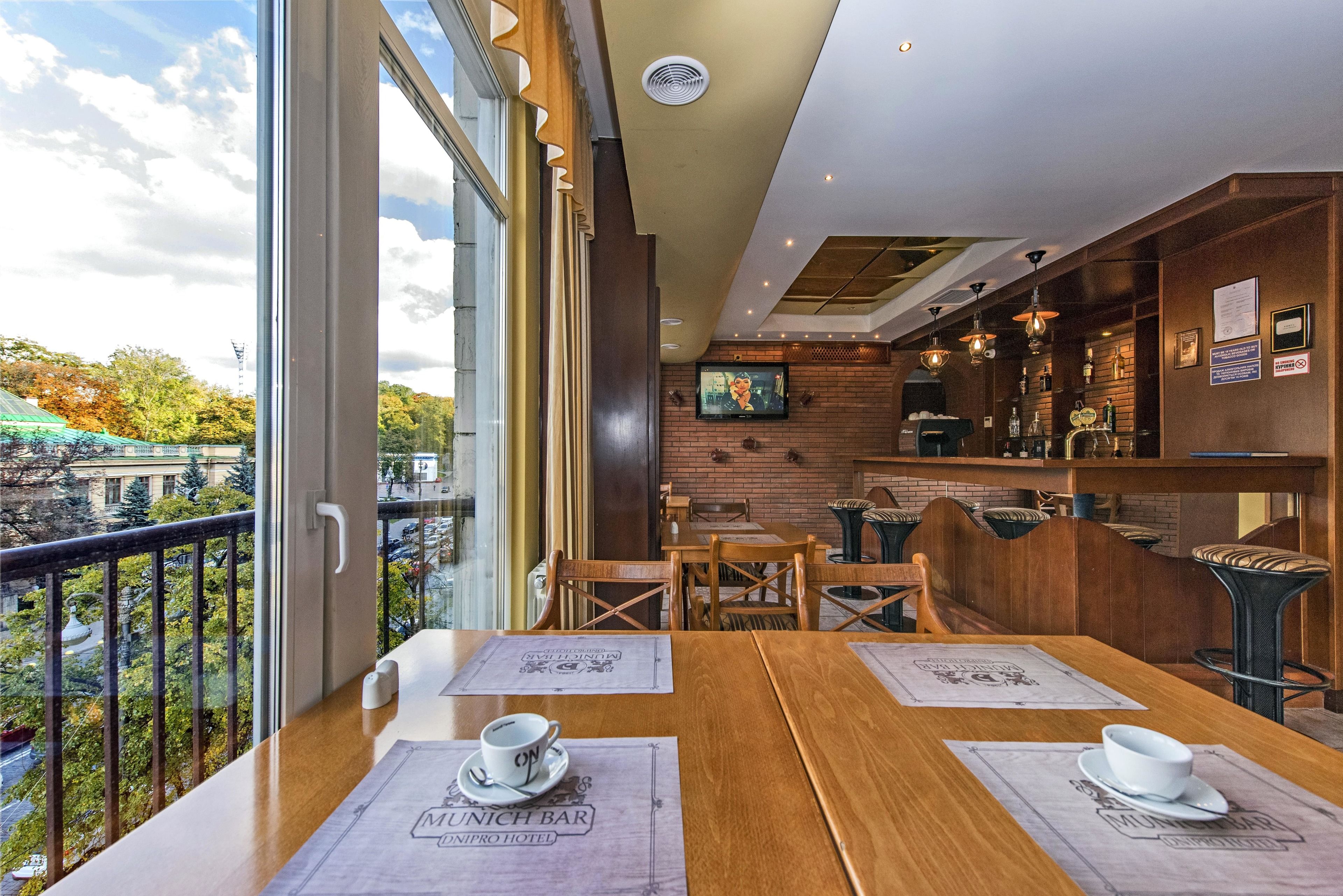 Ein Restaurant mit Holztischen und -stühlen, einer Bar und einem Fernsehbildschirm.