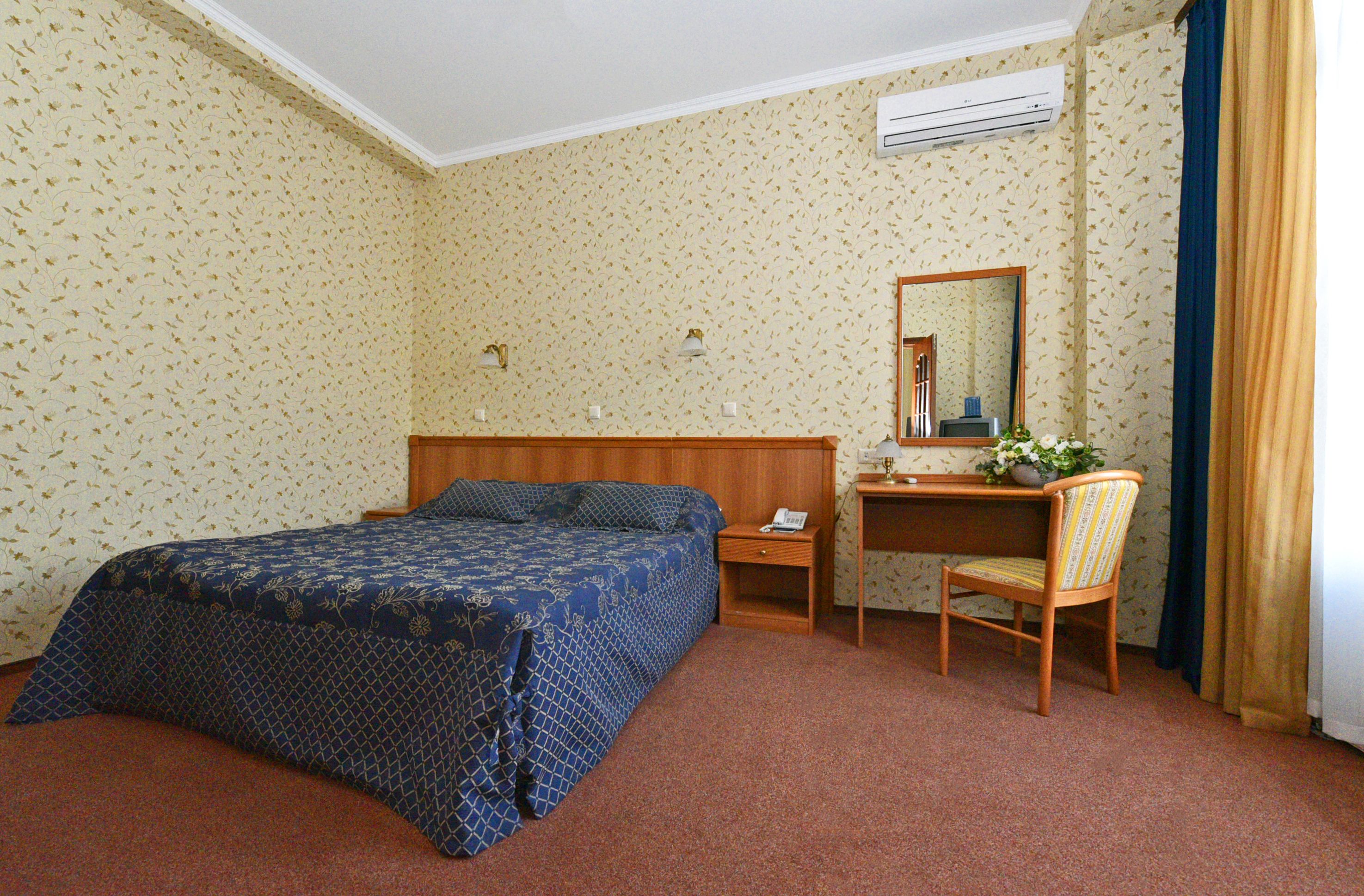 Une chambre d’hôtel équipée d’un lit, d’un bureau, d’une chaise, d’un miroir et d’un appareil de climatisation.