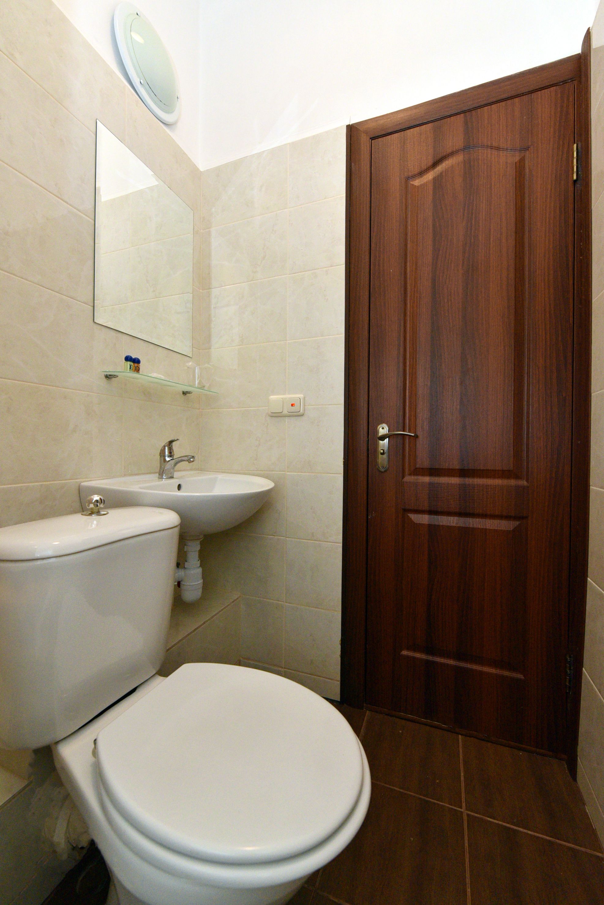 A bathroom with a toilet, sink, and wooden door.