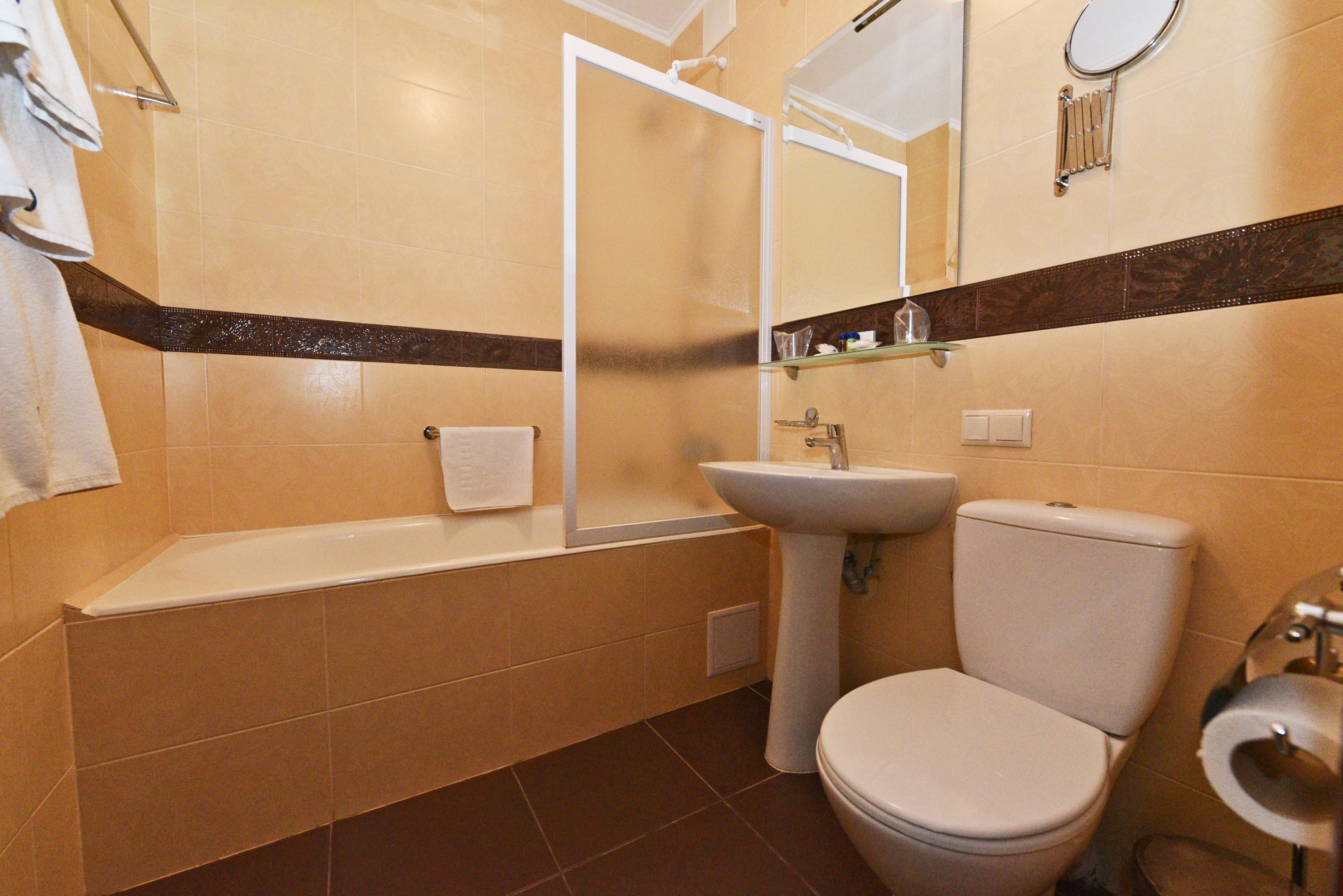 Een badkamer met een bad, wastafel, toilet en een spiegel.