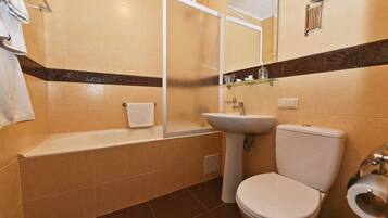 Een badkamer met een bad, wastafel, toilet en een spiegel.