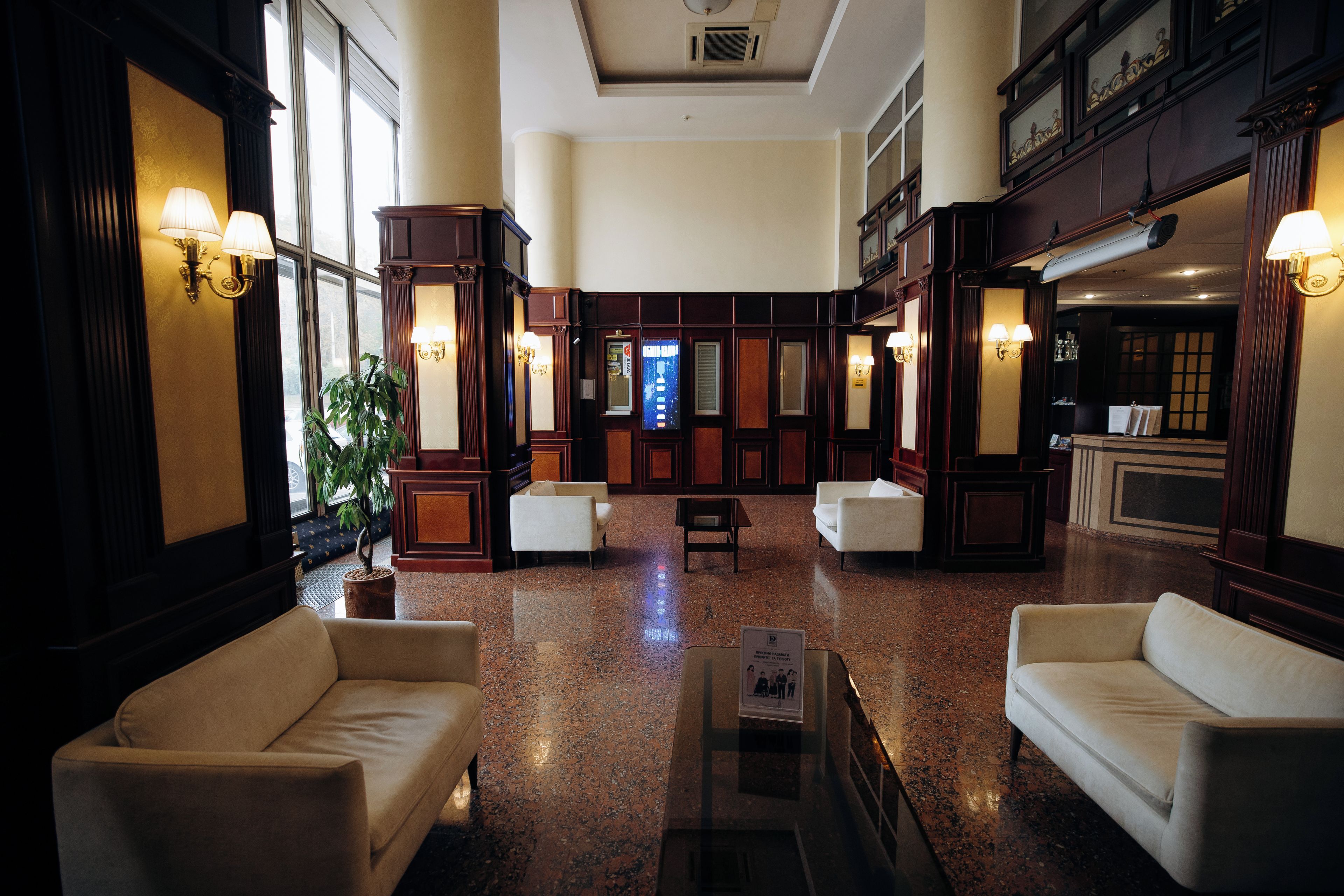 Et hotellobby med et centralt opholdsområde, en receptionsdisk og et stort vindue.