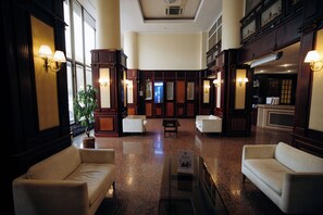 A hotel lobby with a central seating area, a reception desk, and a large window. - Hotel Dnipro (Kyiv)