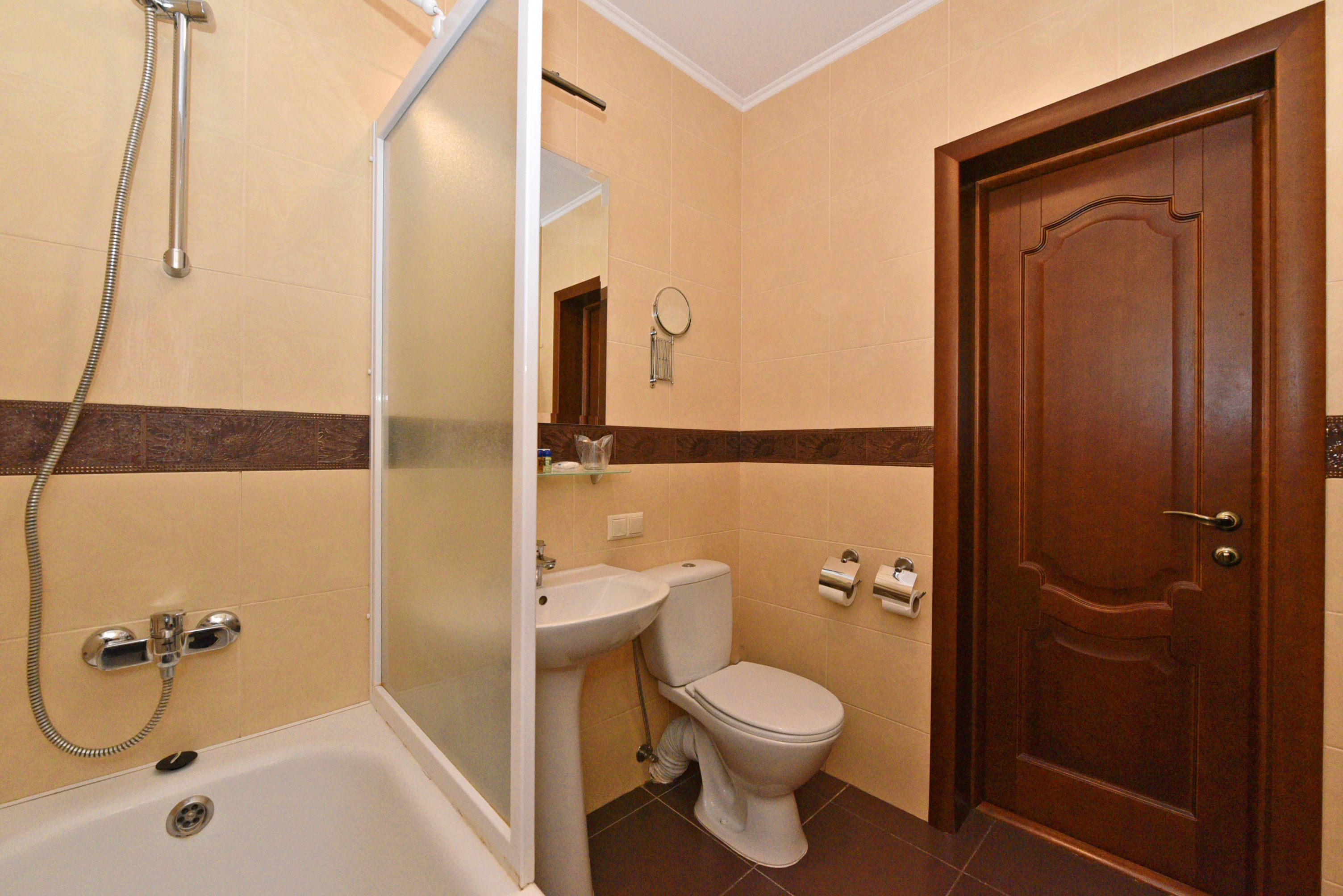 A bathroom with a bathtub, sink, toilet, and a wooden door.