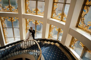 Una gran escalera con vidrieras ornamentales y un elegante suelo de alfombra estampada azul.