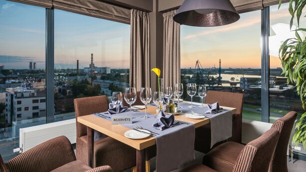 A dining table set for six with a city view, a name card, and a plant on the table. - Ibis Styles Riga (Riga)