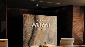 A reception desk with a marble wall, a laptop, and a framed picture. - Mimi Hotel Chisinau (Chisinau)