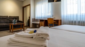 Een hotelkamer met twee bedden, een bureau, een stoel, een bank en een televisie.