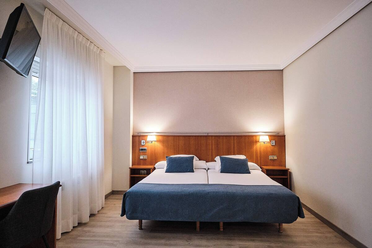 Une chambre d’hôtel avec un grand lit, deux tables de chevet, un bureau et une chaise.