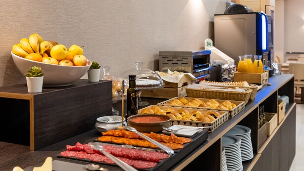 Een buffet met diverse gerechten, waaronder fruit, vleeswaren en gebak.