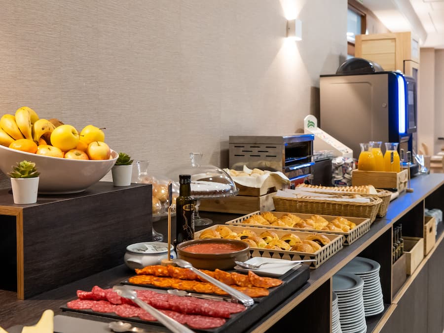Een buffet met diverse gerechten, waaronder fruit, vleeswaren en gebak.