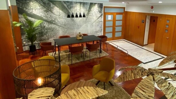 Un hall d’hôtel moderne doté d’un espace repas, d’une grande fresque murale et d’une sculpture en bois originale.
