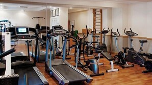 Ein Fitnessraum mit verschiedenen Cardiogeräten, Laufbändern und einer Spiegelwand.