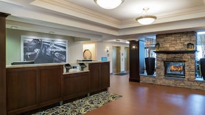 A hotel lobby with a reception desk, a stone fireplace, and a large poster on the wall. - Hampton Inn & Suites Valley Forge/Oaks (Phoenixville)