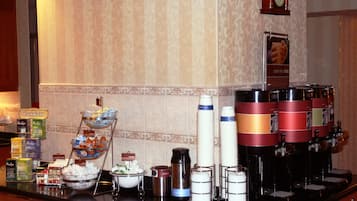 Montaje de bufé con diversas opciones de comida y dispensadores de bebidas.