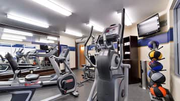 A gym with treadmills, elliptical machines, and a wall-mounted TV.
