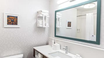 A modern bathroom with a large mirror, white fixtures, and a patterned wall.