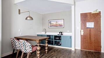 A modern kitchen with a wooden dining table, two patterned chairs, a pendant light, and a microwave.