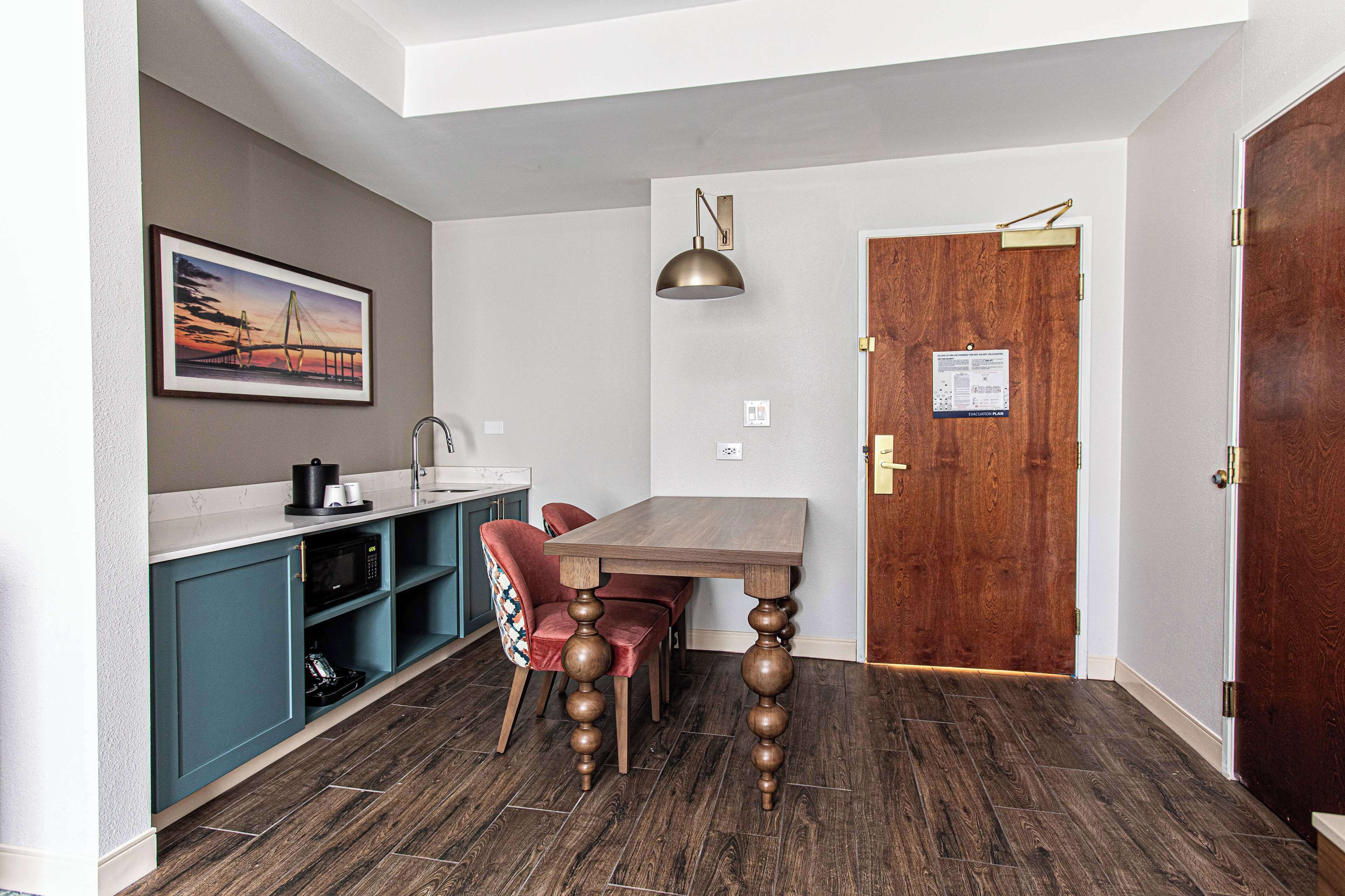 Una cocina moderna con armarios verde azulado, una mesa de comedor de madera y una lámpara colgante.