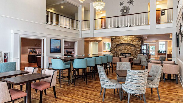 A spacious lobby with a high ceiling, a stone fireplace, multiple seating areas, and a second-floor balcony. - Hampton Inn & Suites Charleston/West Ashley (Charleston)