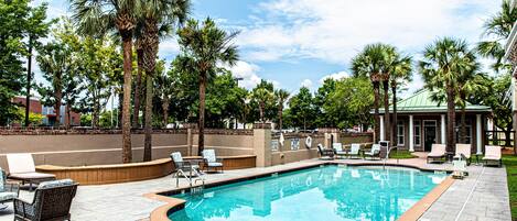 A swimming pool with lounge chairs and palm trees.