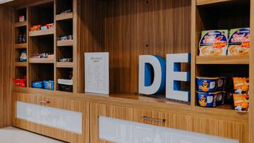 A wooden display with shelves containing various packaged goods and a sign with the text 'THE SWEET SHOP.'