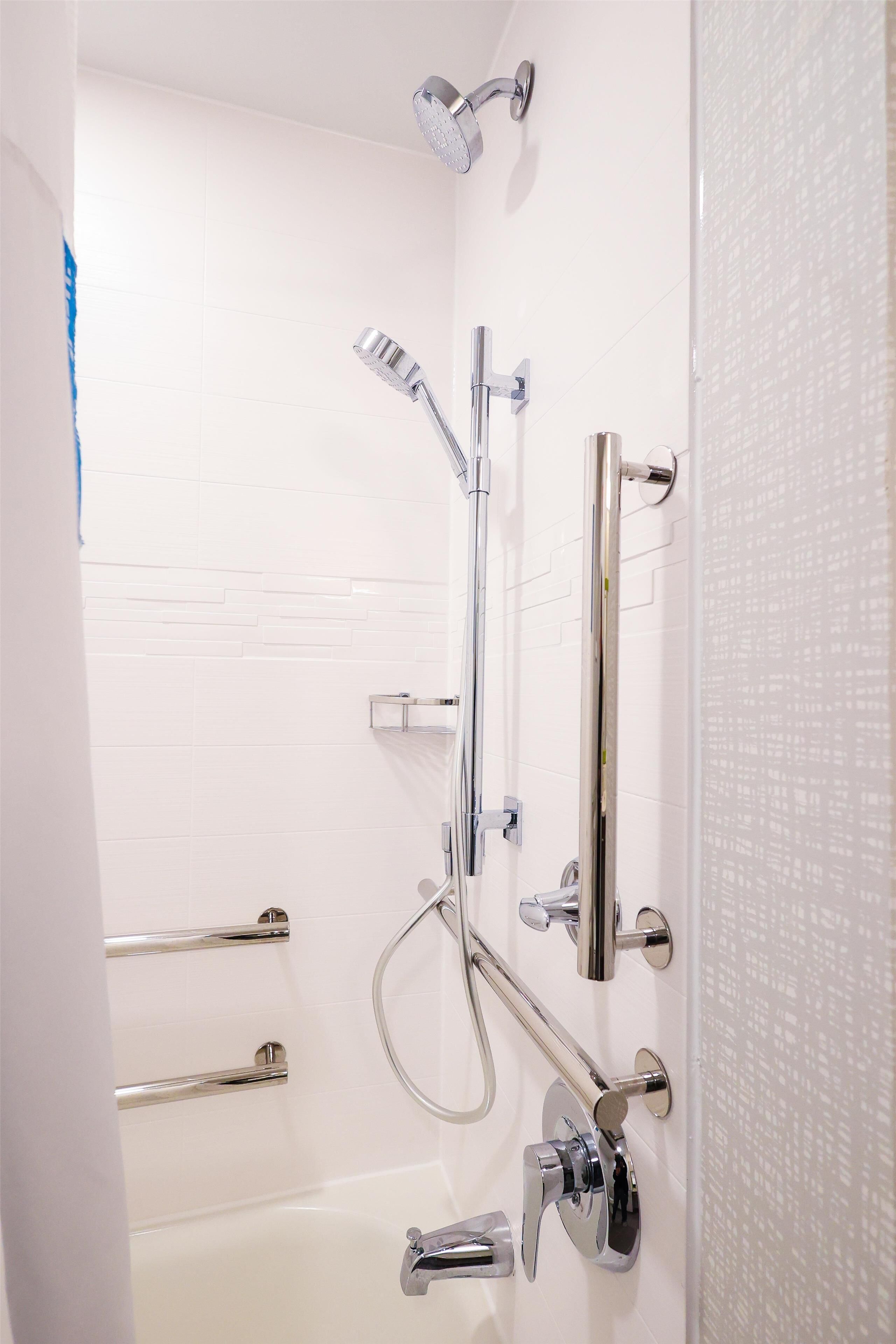 Un baño con bañera, una ducha y múltiples cabezales de ducha manuales.