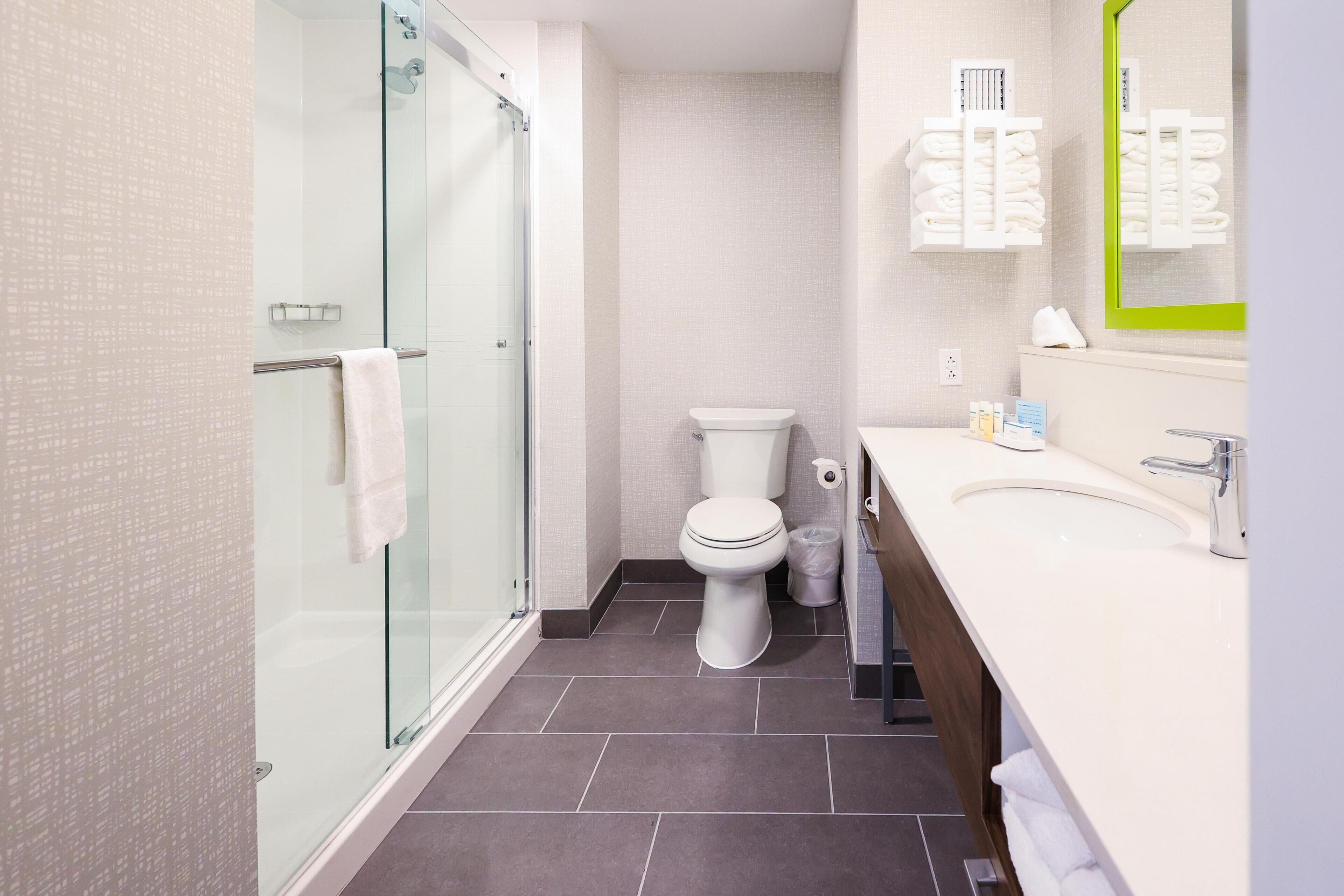 A modern bathroom with a glass shower enclosure, a toilet, and a sink with a mirror.