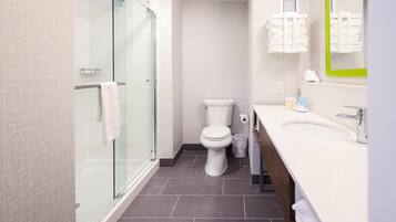 Un baño moderno con cabina de ducha de vidrio, inodoro y lavamanos con espejo.