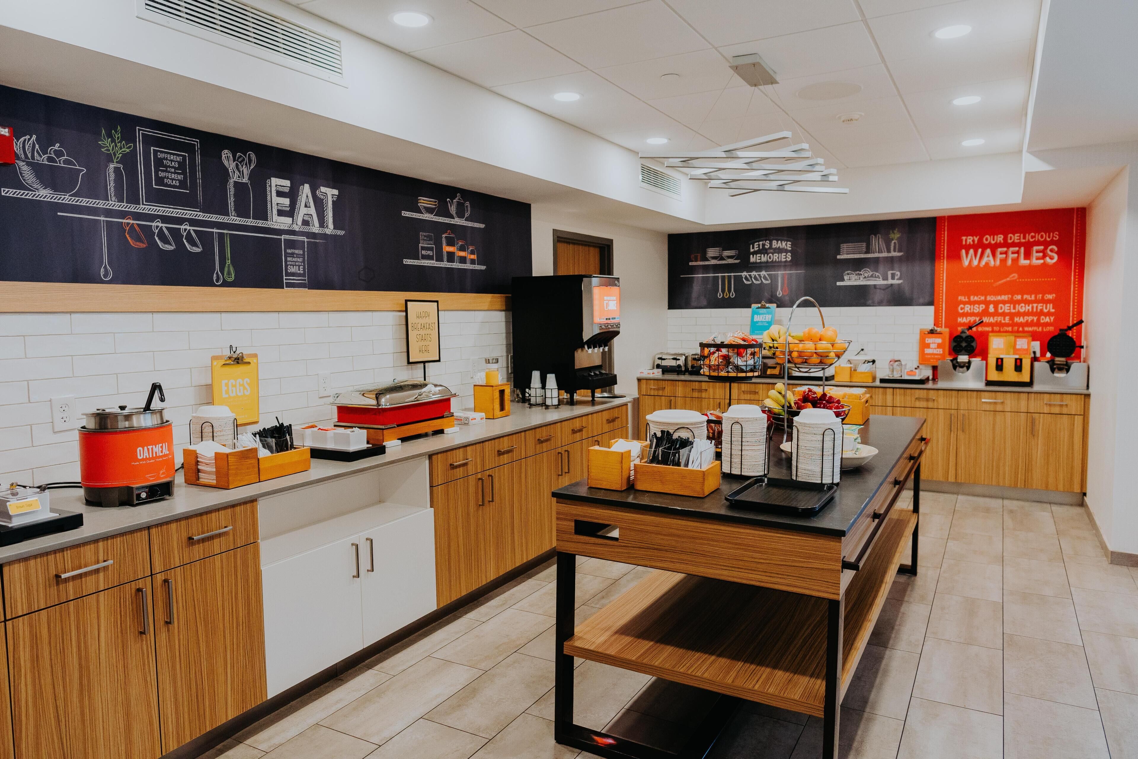 Een moderne keuken met een koffieapparaat, een fruitmand en een stapel wafels.