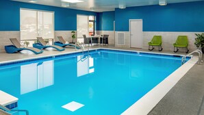 Una piscina con sillones de descanso, una mesa y sillas.