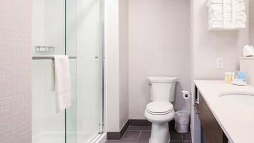 A modern bathroom with a glass shower enclosure, a toilet, and a vanity with a towel rack.