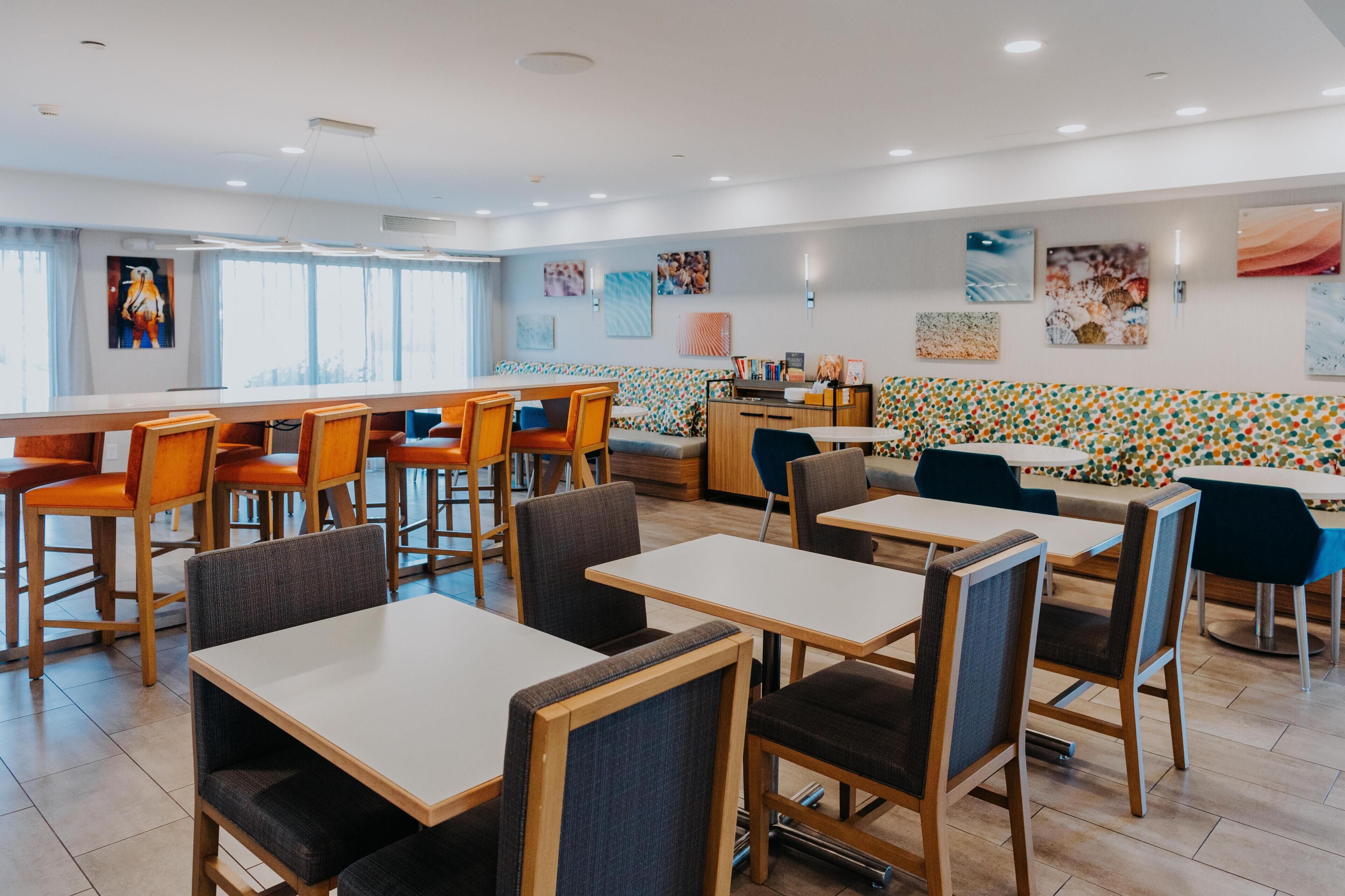 Un comedor moderno con mesas y sillas, un sofá y obras de arte en las paredes.