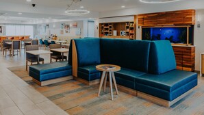 Un espacio lounge moderno con asientos, una pequeña mesa y un acuario grande.