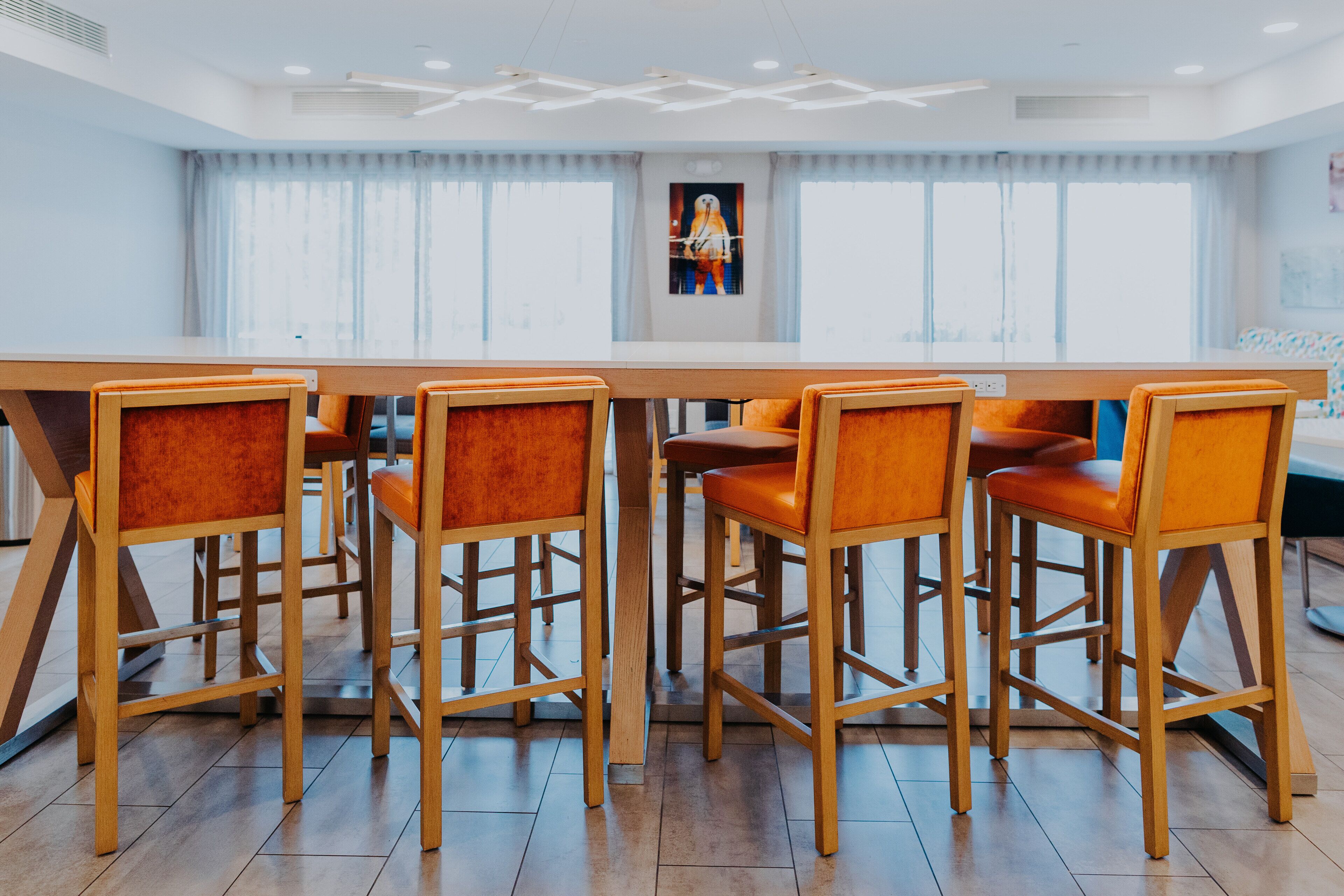 A conference room with a long table and four wooden chairs with orange upholstery.