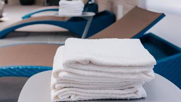 A stack of white towels on a table in a room with a blue wall and a pool area.