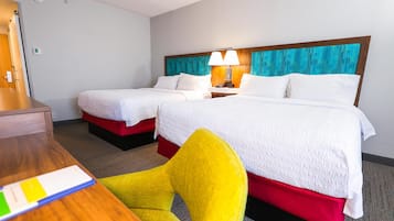 A hotel room with two beds, a desk, and a chair.