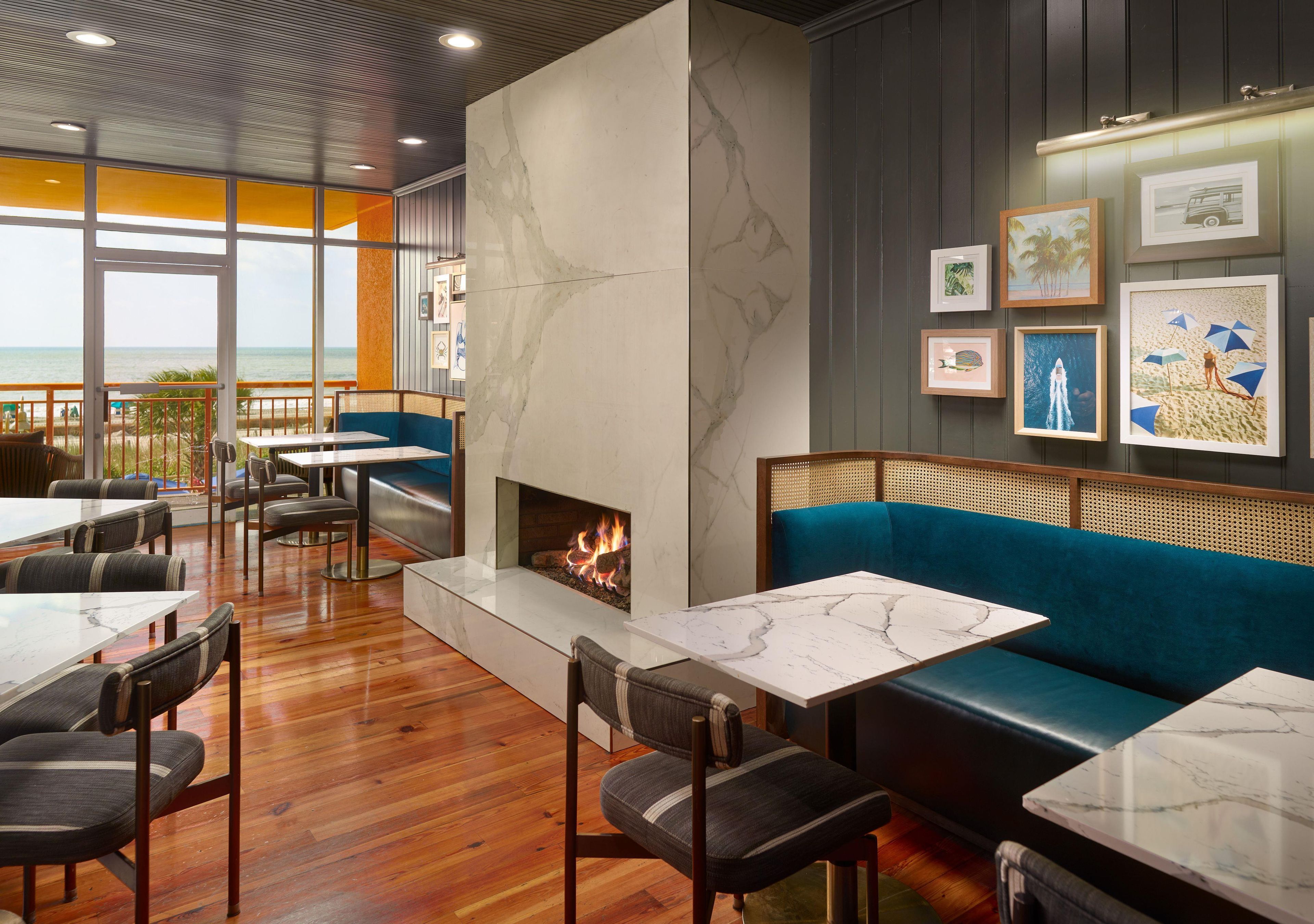 A restaurant with a fireplace, wooden flooring, and a view of the beach.