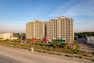 Un hotel de gran altura con varias plantas, vista al mar y zona de estacionamiento.