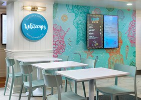A restaurant interior with a menu board, tables, and chairs.