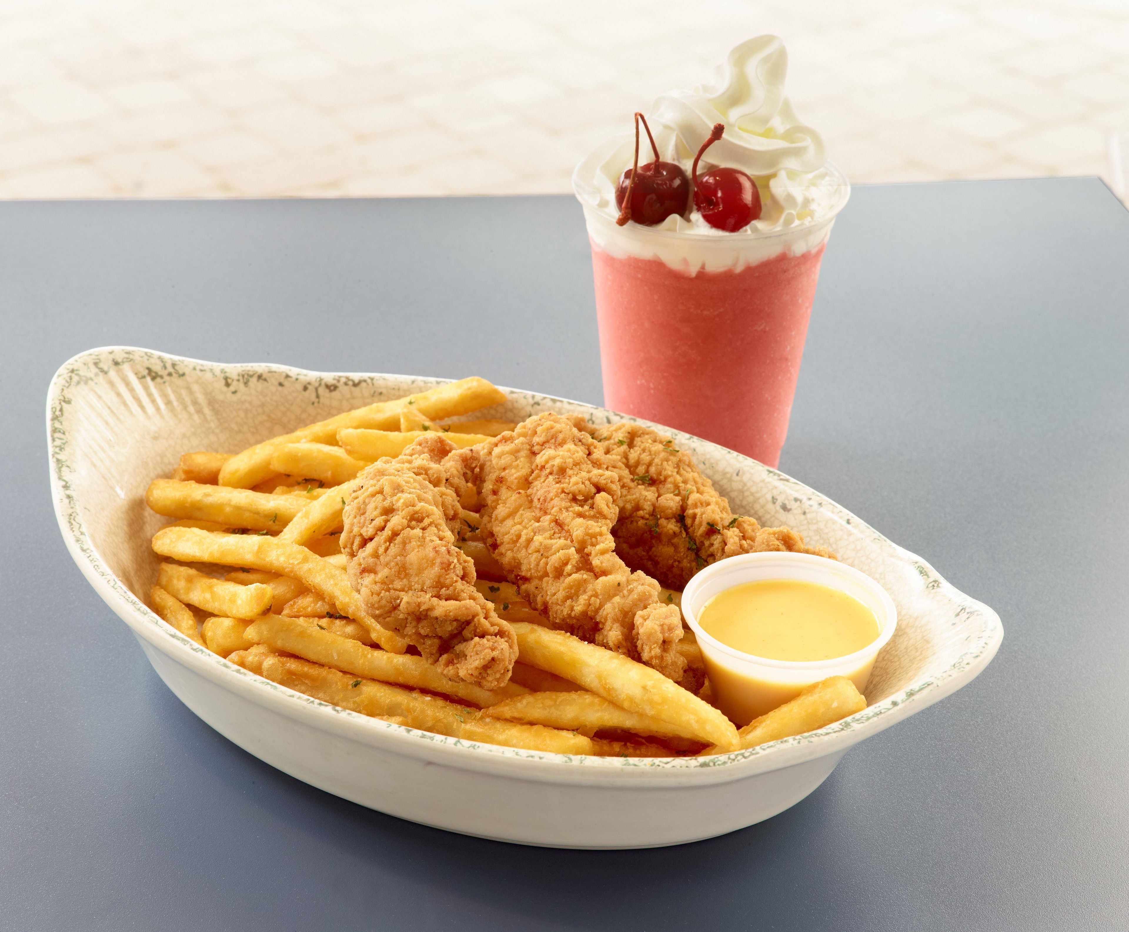 A meal consisting of fried chicken, French fries, and a beverage with whipped cream and cherries.