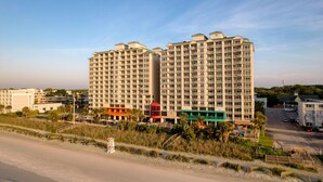 A high-rise hotel with multiple floors, a beach view, and a parking area.