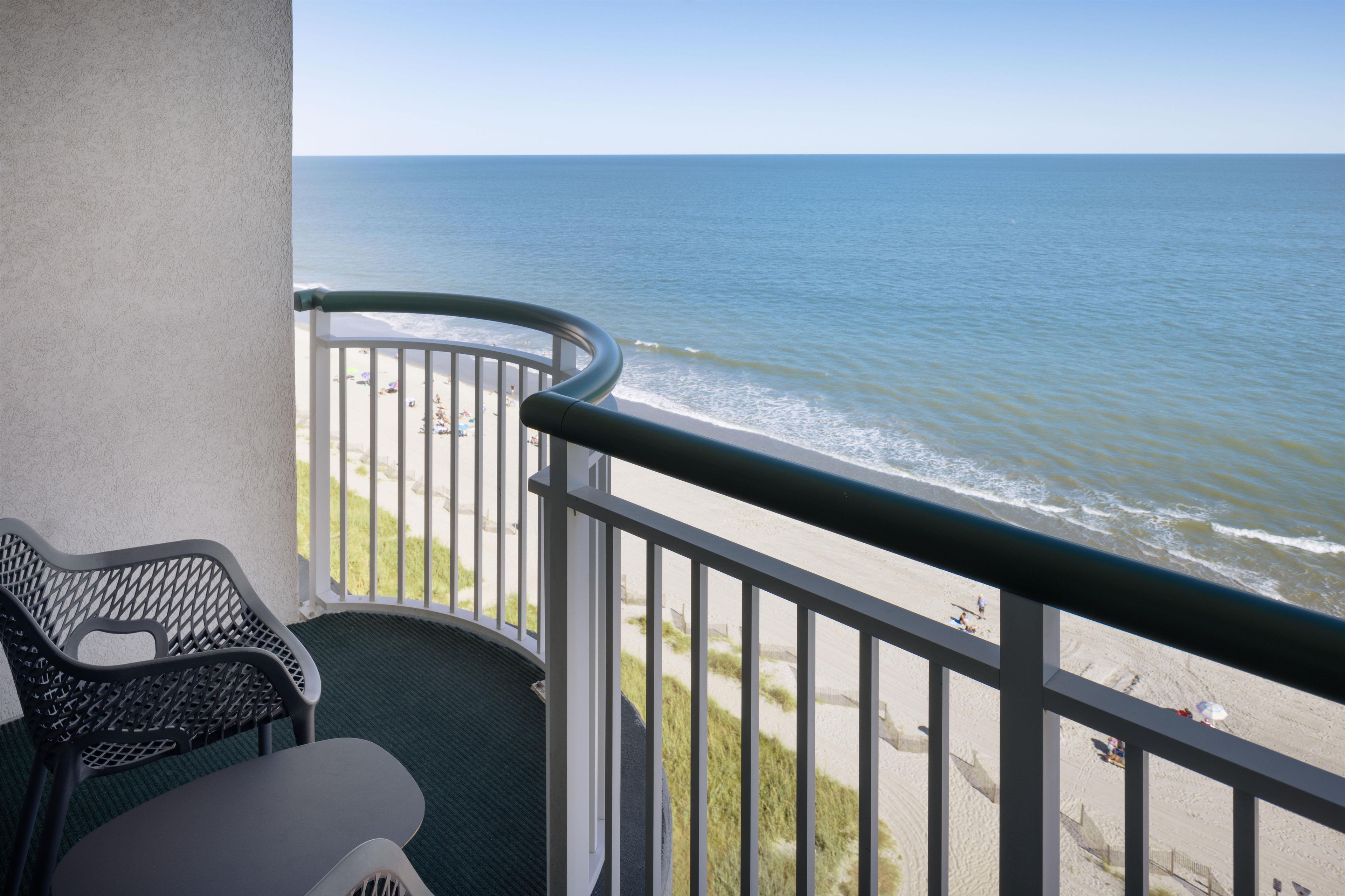 A balcony with a view of the beach and ocean.