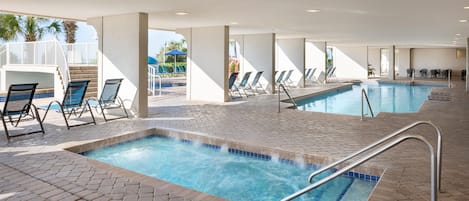 A hotel pool area with multiple pools, lounge chairs, and a covered seating area.