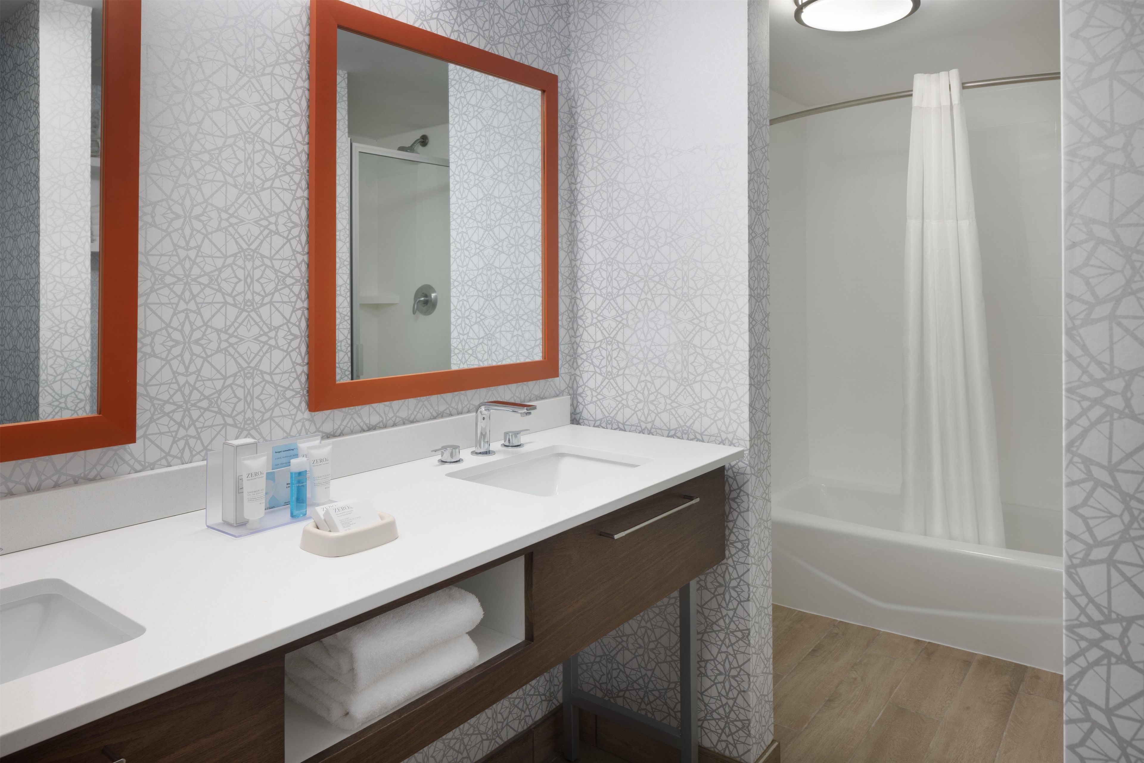 Un baño con dos lavamanos, un espejo y una ducha.