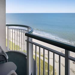 Enjoy the ocean view from this balcony with a curved railing and seating area.