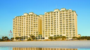 A multi-story hotel with balconies, located near a beach with visible waves. - Hampton Inn & Suites Myrtle Beach/Oceanfront (Myrtle Beach)