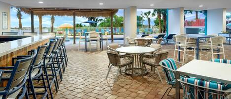 A bar area with seating, a pool view, and a covered patio.