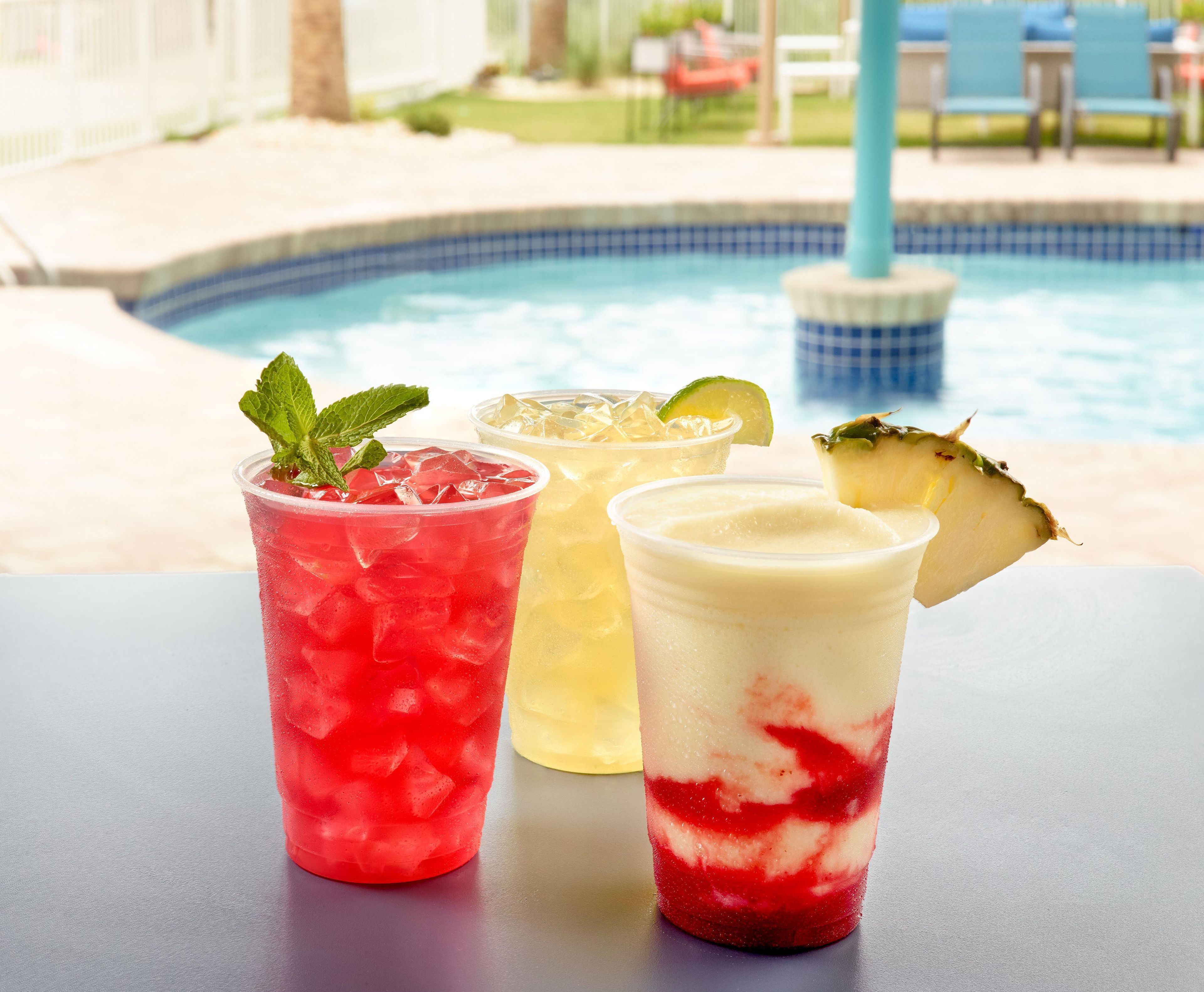Trois boissons sur une table près d’une piscine.